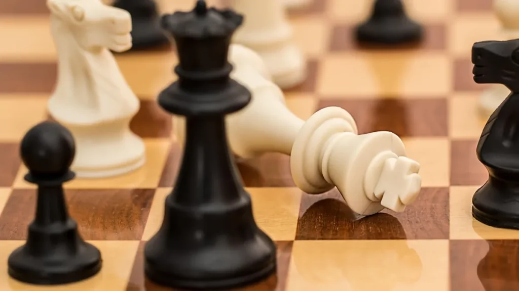 A white king piece lies fallen on a chessboard surrounded by standing black pieces, symbolizing a strategic defeat.