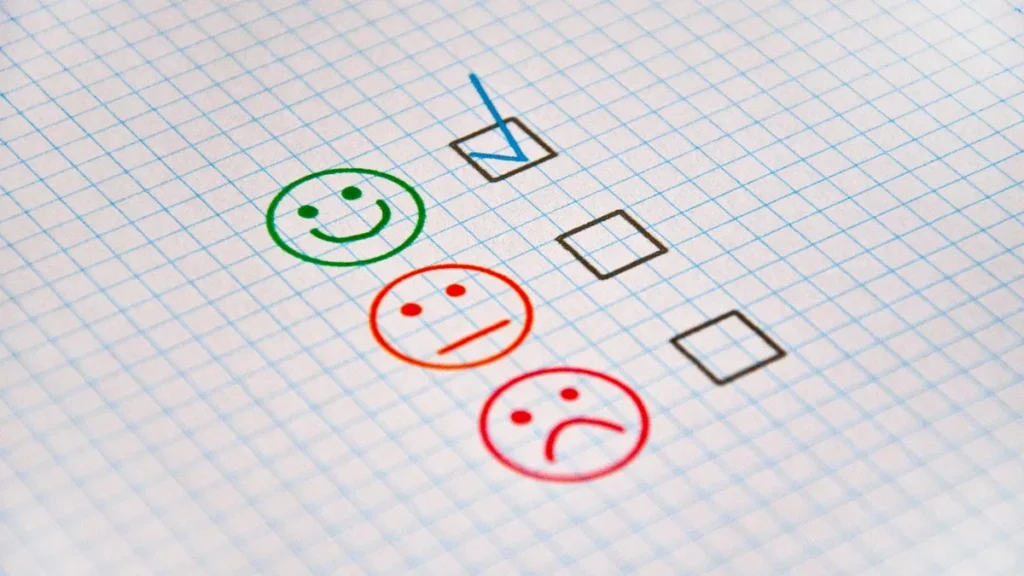 A checklist on graph paper with a blue tick next to a green happy face, indicating a positive selection.