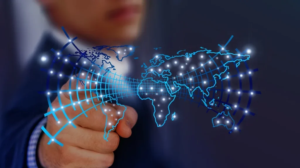 Glowing blue digital world map grid with bright nodes, pointed to by a blurry businessman.