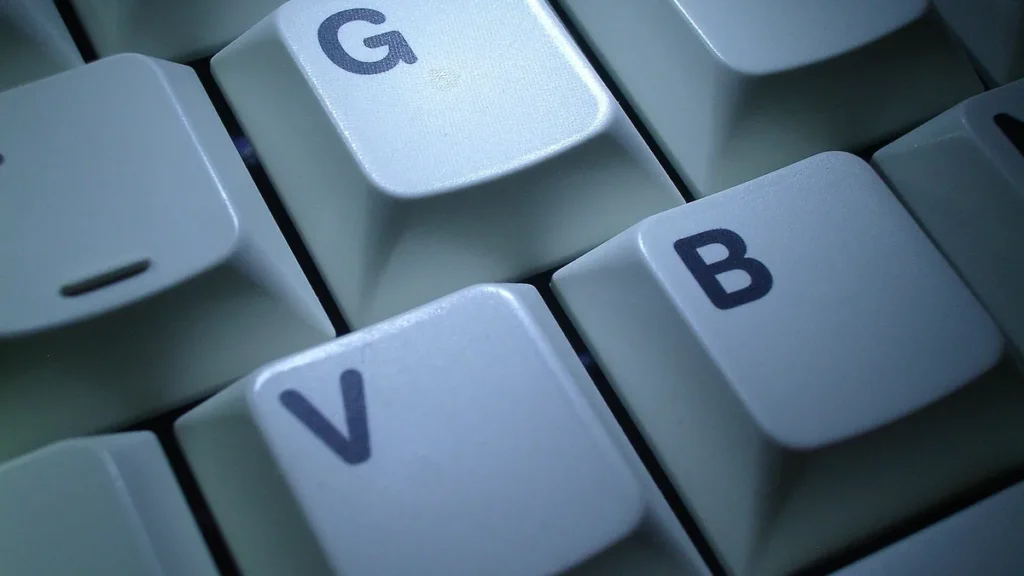Close-up of white computer keyboard keys showing the letters G, V, and B under cool blue lighting.