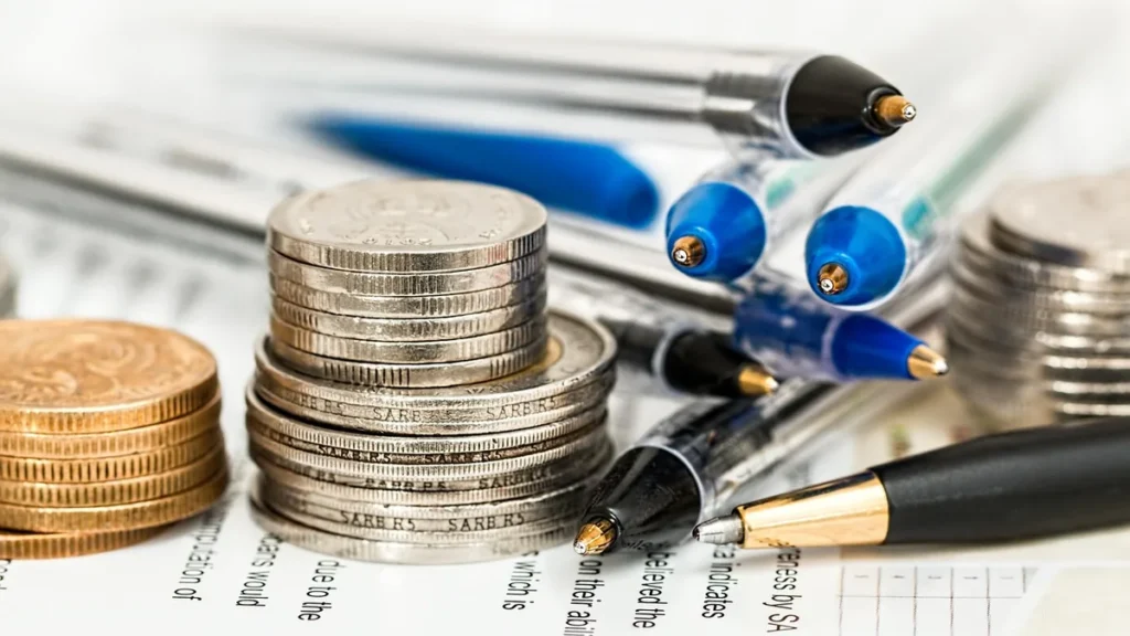 Stacks of coins and pens resting on a financial document, symbolizing corporate finance.
