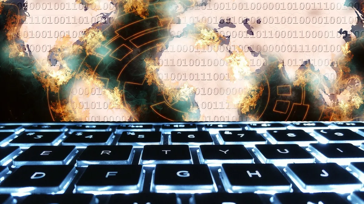 Backlit keyboard with a fiery world map and binary code representing global cybersecurity threats.