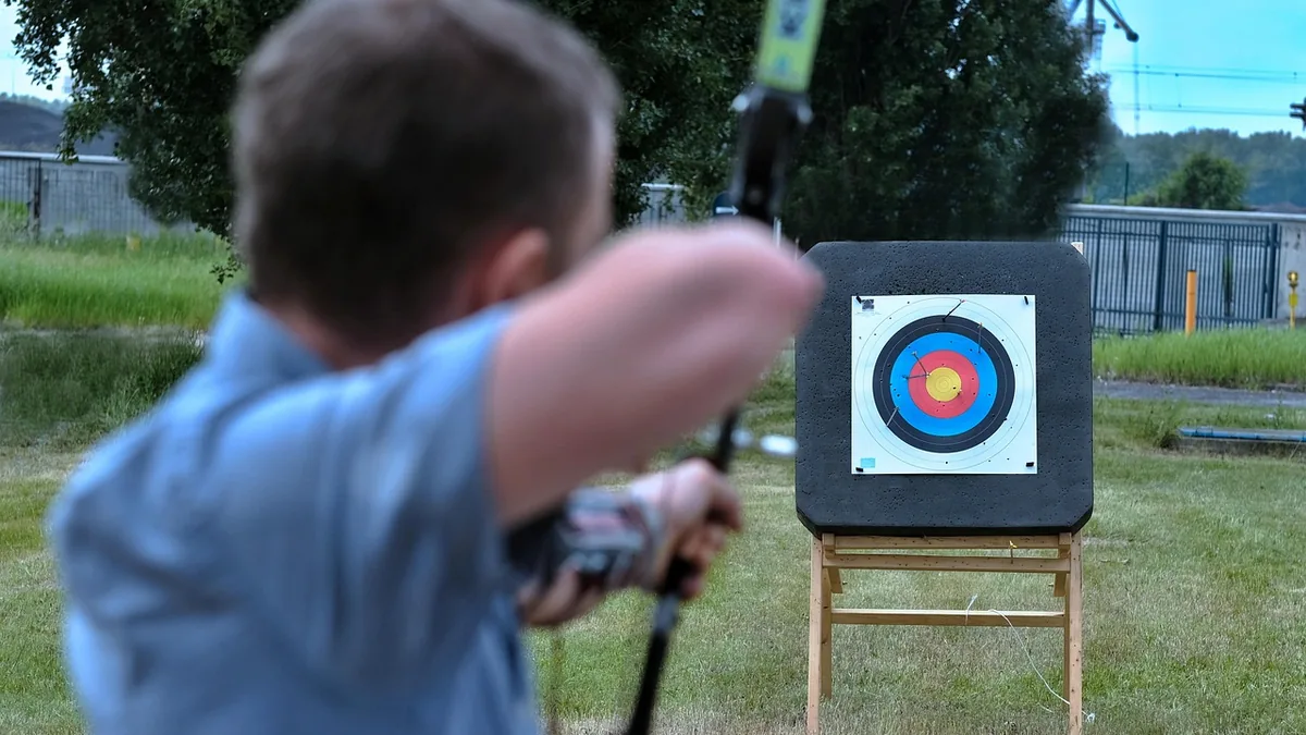A person aims a bow and arrow at a colorful archery target, symbolizing targeted strikes.