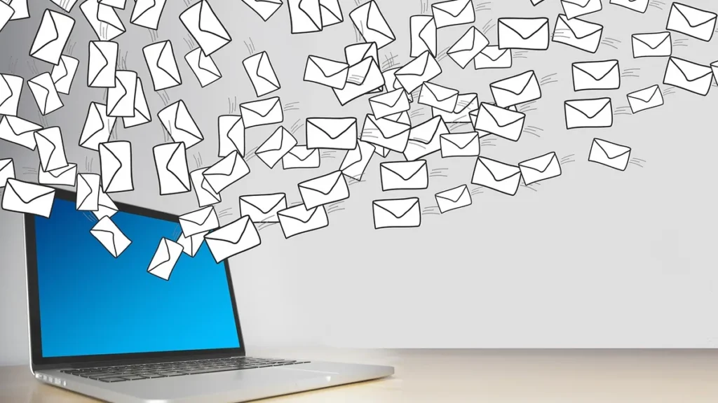 Cartoon envelopes flying out of a laptop with a blue screen, visualizing a massive email bombing campaign.