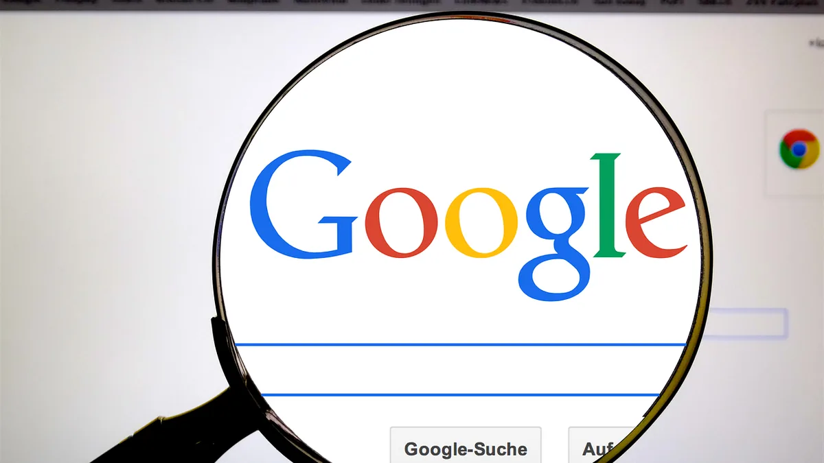 Magnifying glass focusing on the colorful Google logo on a screen, symbolizing search investigation.