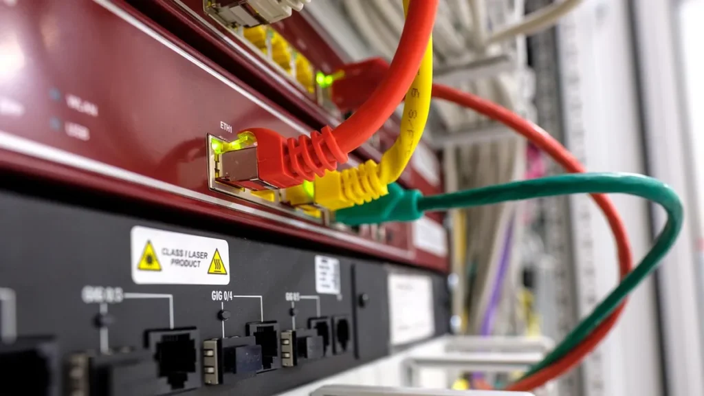 Close-up of colorful ethernet cables plugged into network ports on a server switch with status lights.
