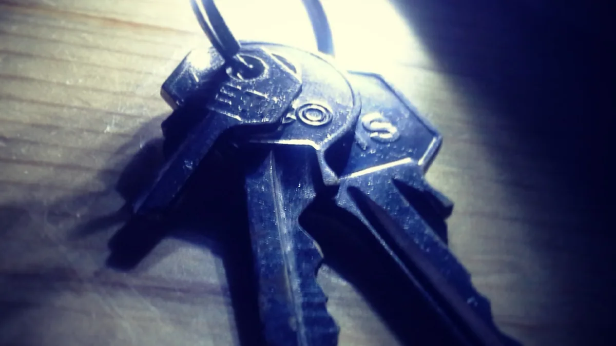 Close-up of metal keys on a keyring under dramatic blue lighting on a wooden surface.