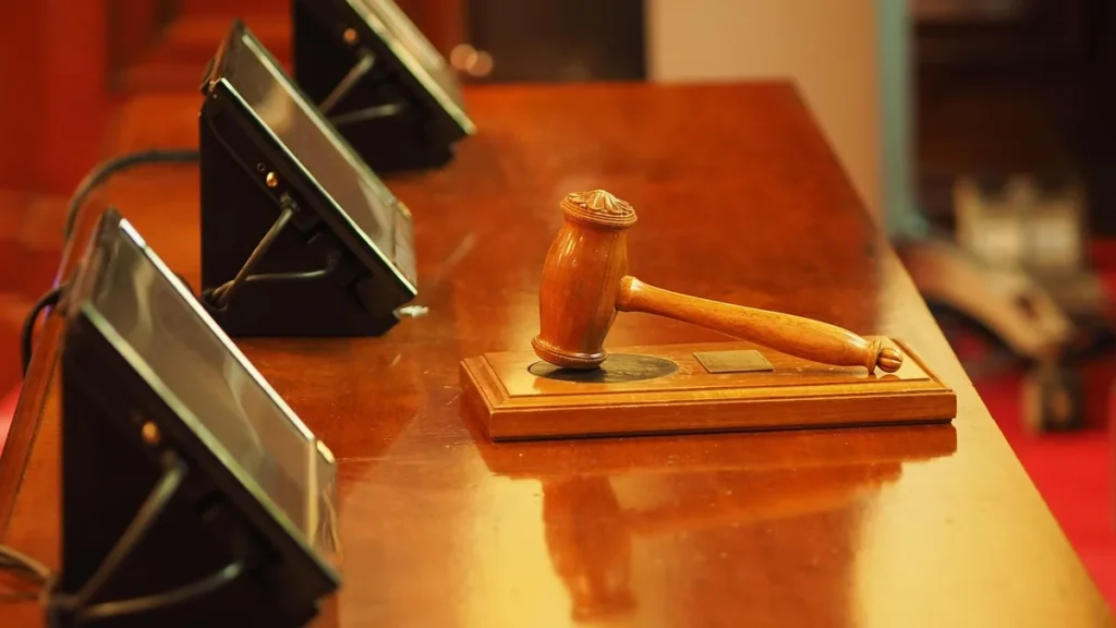 A wooden judge's gavel rests on its sound block on a polished wooden desk.