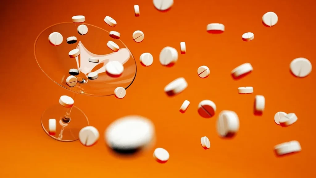 White pills falling through the air around a martini glass against an orange background.