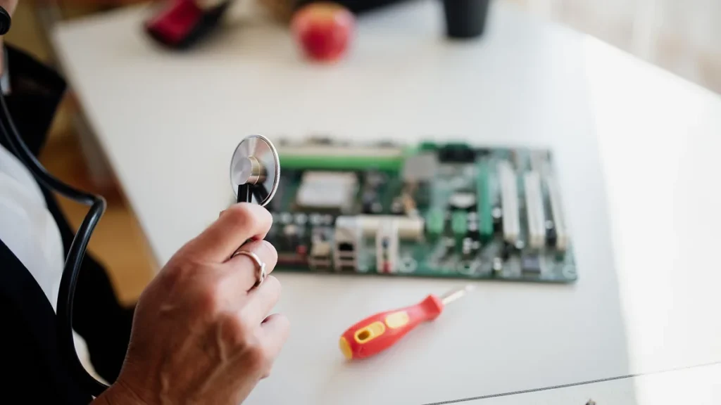 A hand holding a stethoscope over a computer motherboard, symbolizing the diagnosis of tech vulnerabilities.