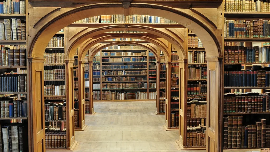 A grand library with wooden arches and shelves filled with old, leather-bound books.