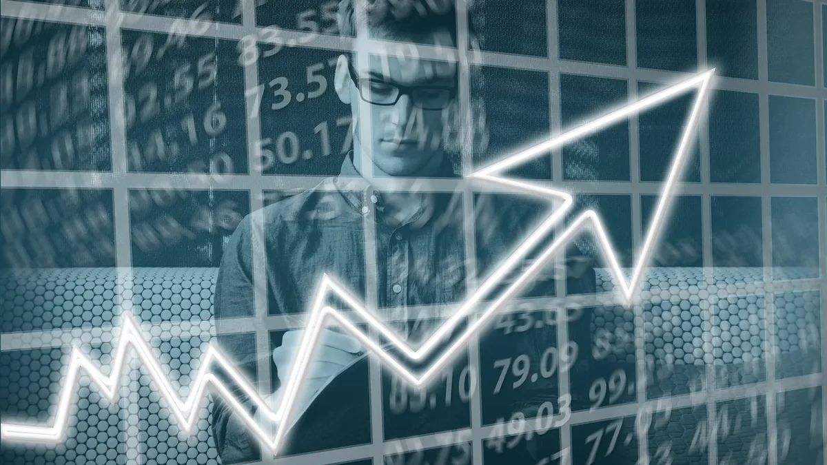 A man in glasses behind a glowing arrow pointing upwards over a grid of financial numbers.