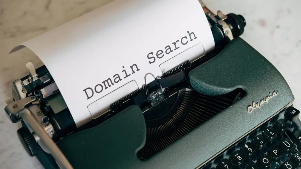 A close-up shot of a vintage green Olympia typewriter with paper that reads 'Domain Search'.