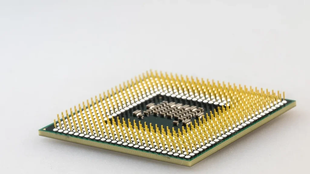 Close-up of a gold-pin computer processor chip on a white background.