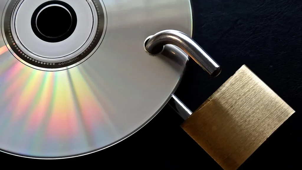 A silver CD with a brass padlock locking through a hole, representing data security.