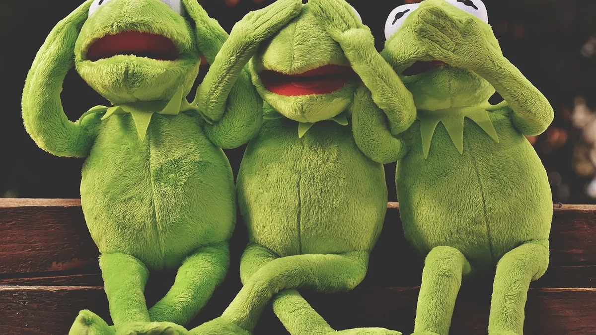 Three green frog plush toys in the classic three wise monkeys poses, representing ignoring risks.