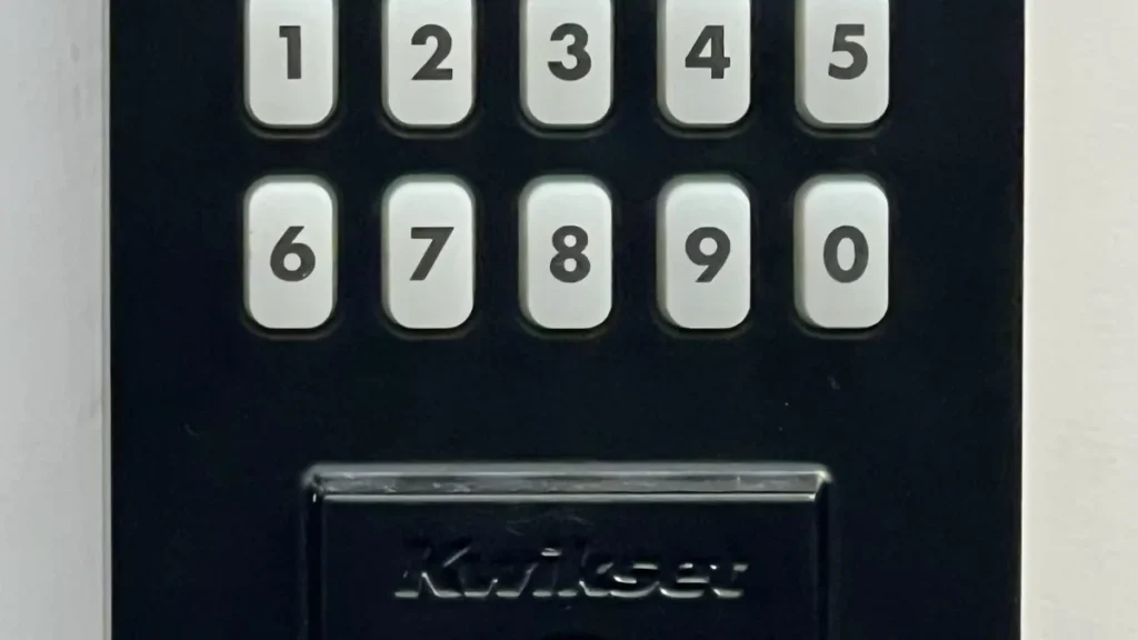 Close-up of a black Kwikset keypad lock with white buttons showing numbers 1 through 0.