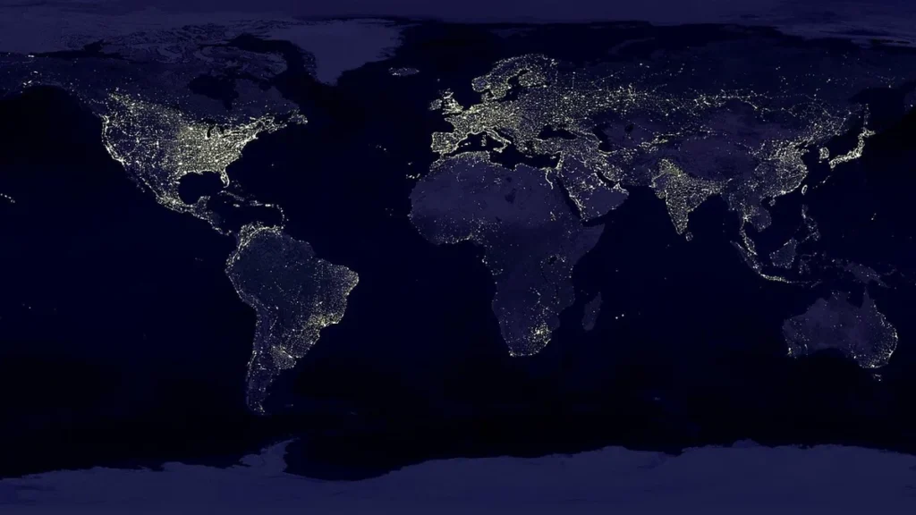 Satellite view of Earth at night, showing glowing city lights across the global continents.