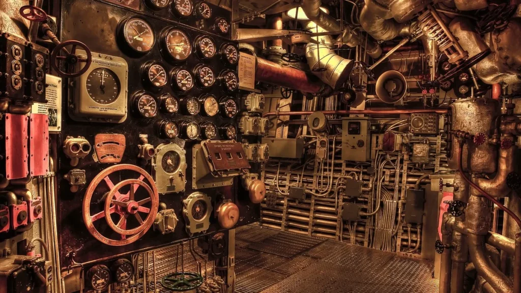 An old-fashioned, warm-toned industrial control room filled with analog dials, pipes, and a large red valve wheel.