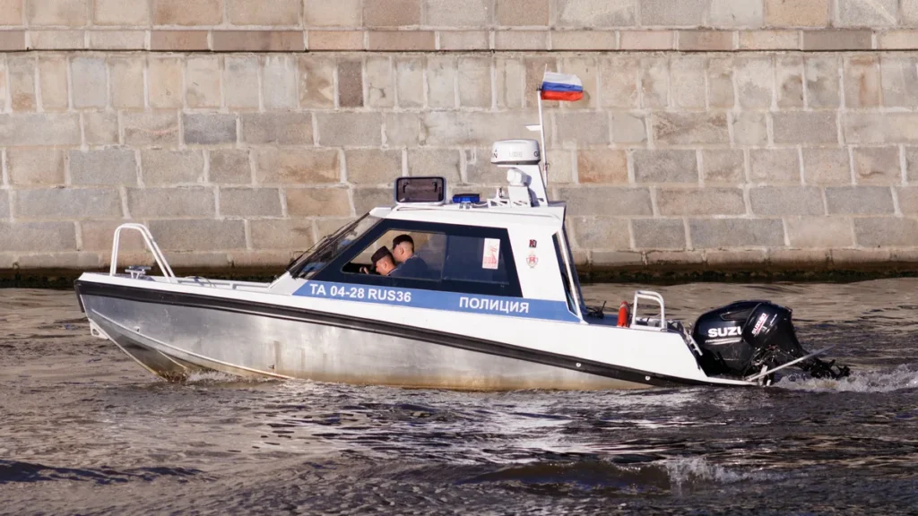 Russian police boat with officers cruising on water, showing Russian flag and 'POLITSIA' marking.