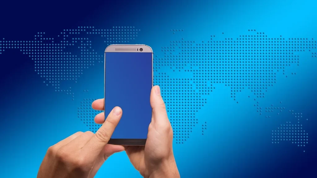 Hands holding a smartphone with a blue screen against a blue background with a dotted world map.