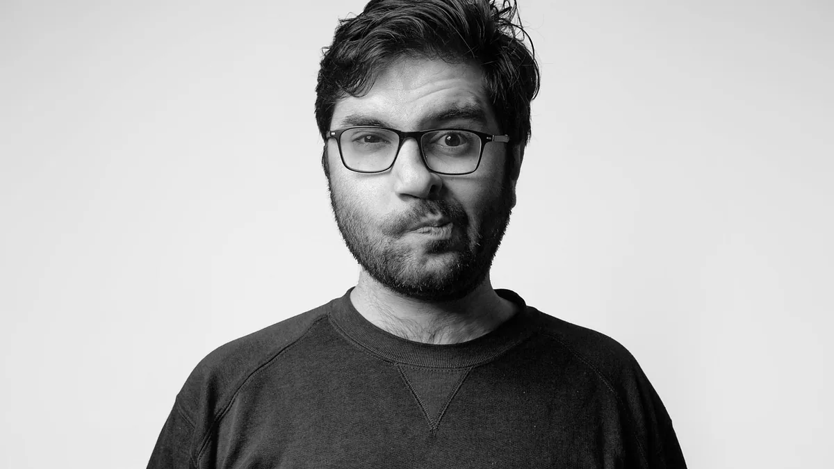 Portrait of a person in professional attire with glasses, neutral expression