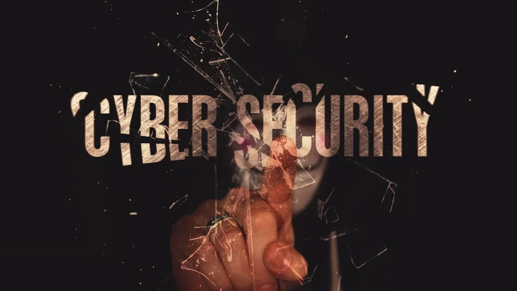 A hand touches shattered glass overlaying the metallic text 'CYBER SECURITY' on a dark background.