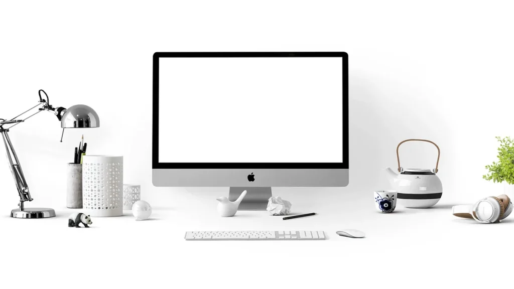 Clean white workspace with an iMac, keyboard, mouse, teapot, and desk lamp.