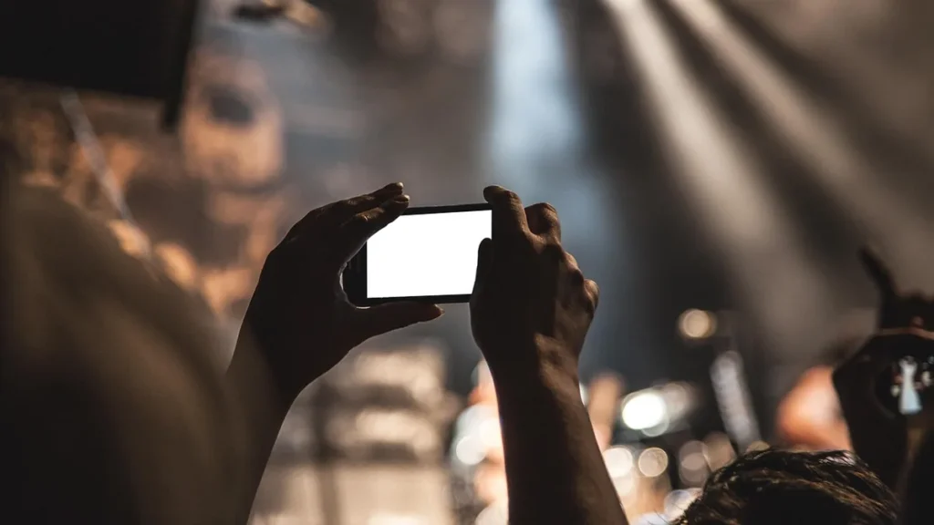 A blurred crowd recording a conference event with a smartphone