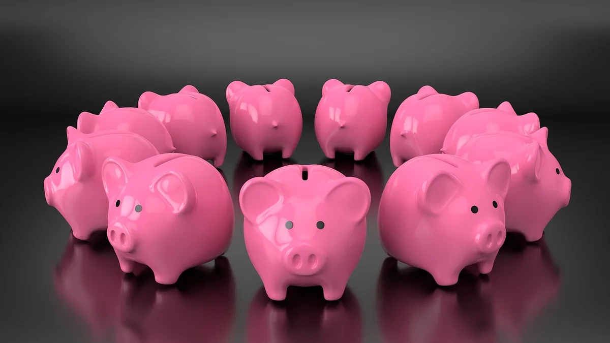 Glossy pink piggy banks arranged in a circle on a dark reflective surface.
