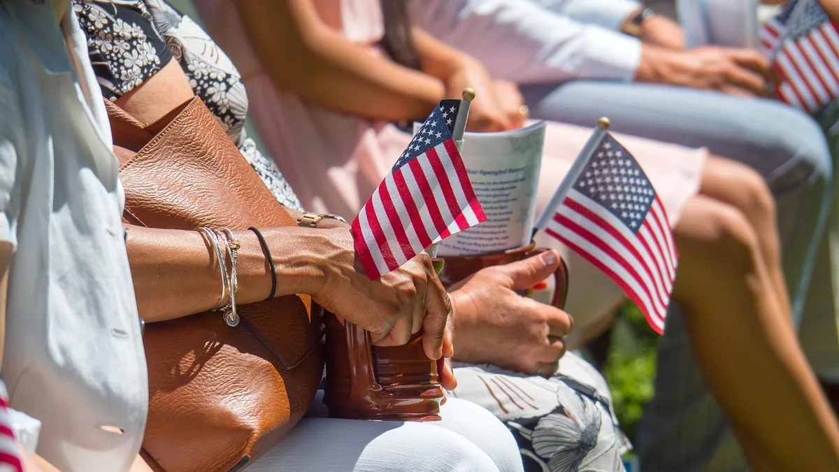 People sitting in a row holding small American flags, representing US travelers.
