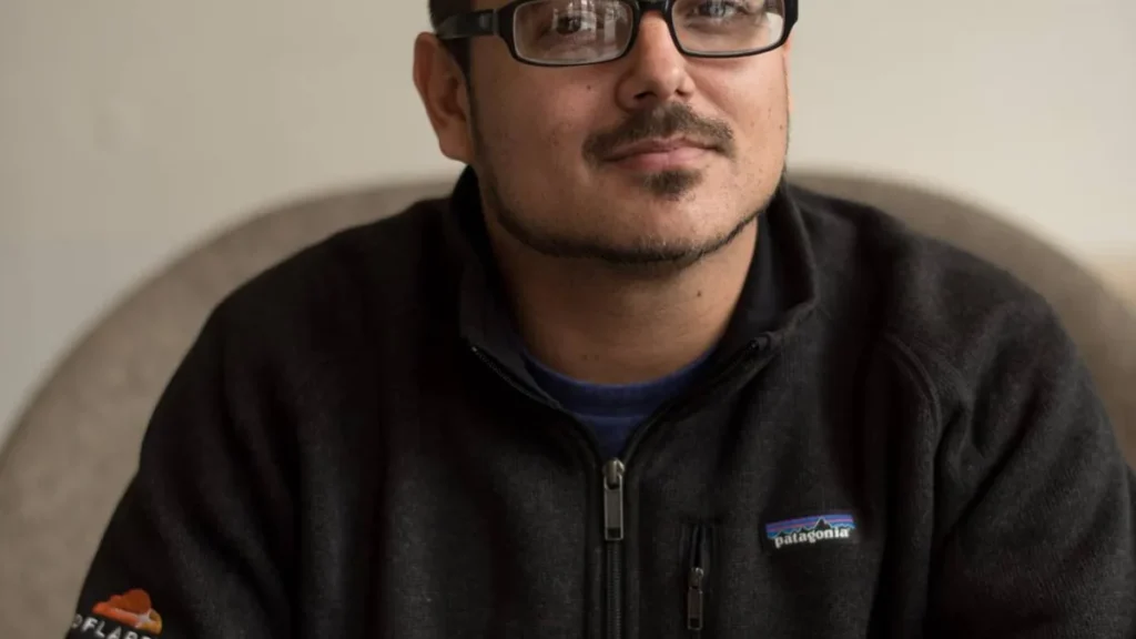 Portrait of a man with glasses wearing a black Patagonia fleece jacket with a visible Cloudflare logo on the sleeve.