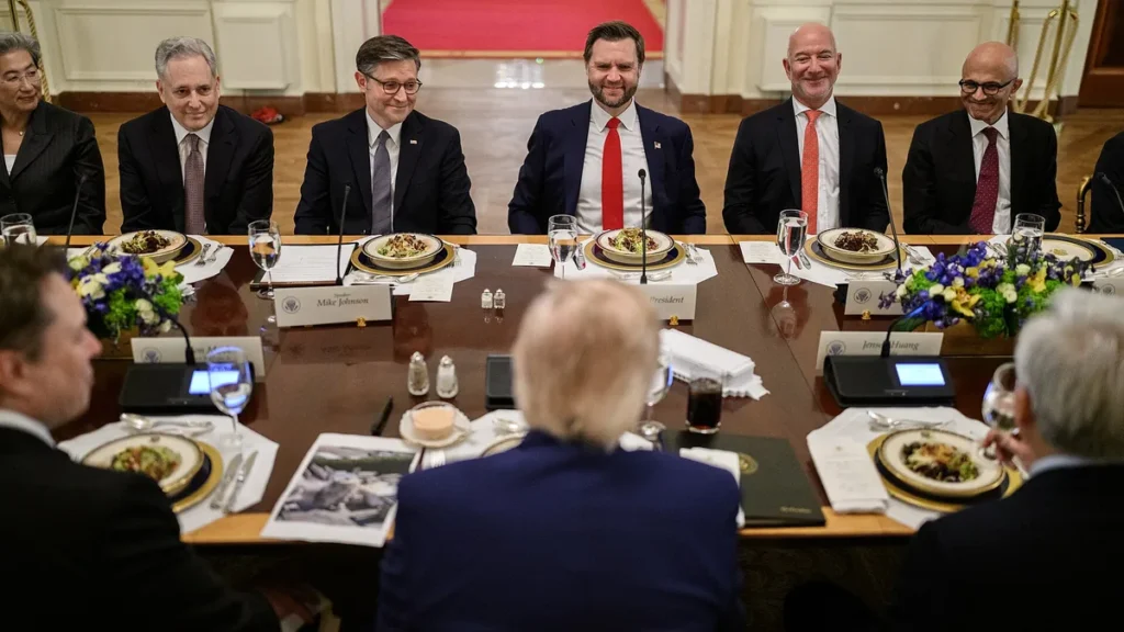 A group of men in suits sit at a long dining table during an official meeting.