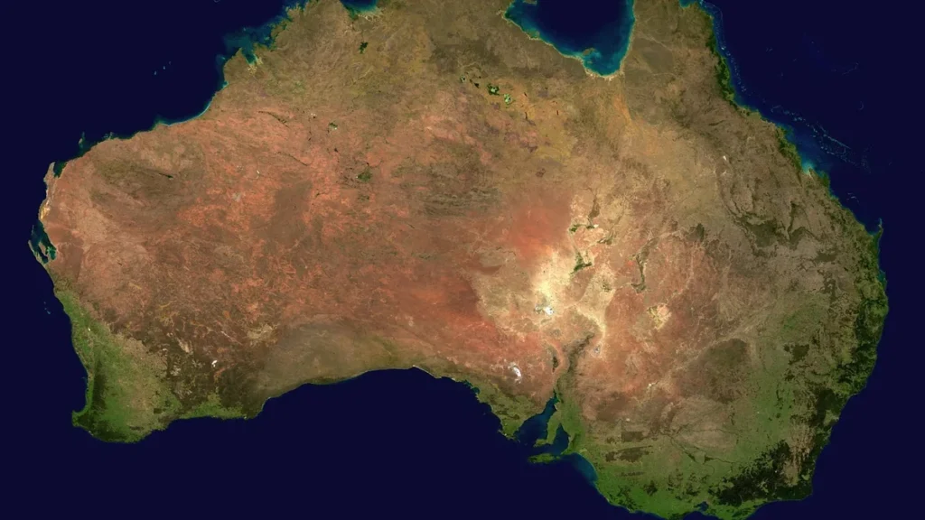 Satellite view of Australia showing its red desert interior and green coastal margins.