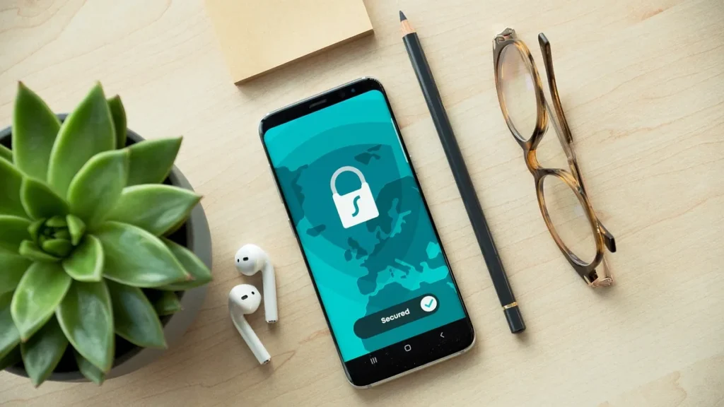 A smartphone on a desk shows a security app with a lock icon and a world map background.